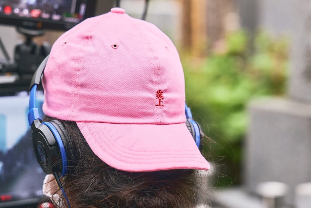 「炎上」と書かれたピンク色の帽子